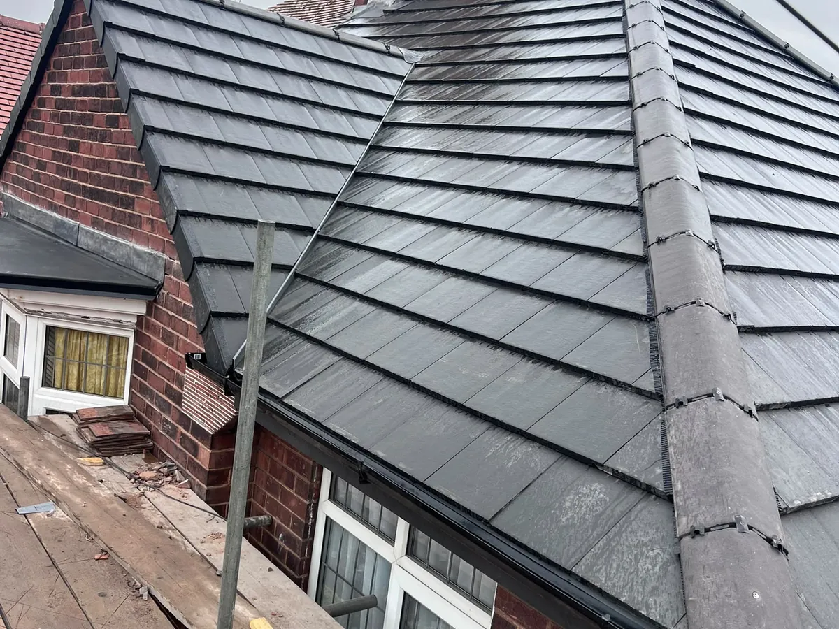 Hipped roof re-covered in grey tiles beside the chimney